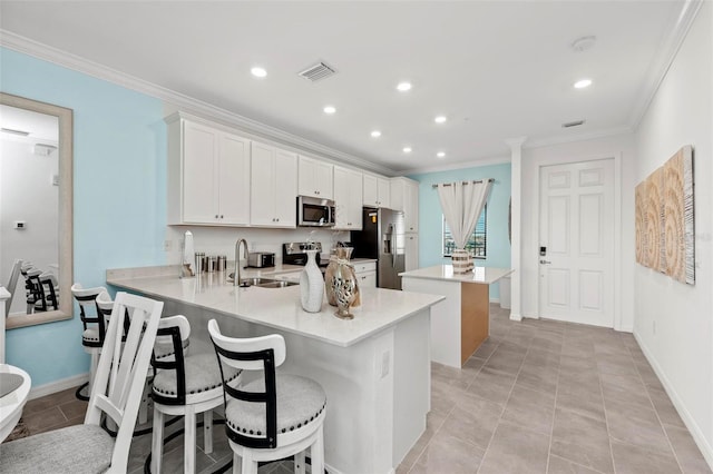 kitchen with stainless steel appliances, sink, white cabinets, kitchen peninsula, and a breakfast bar