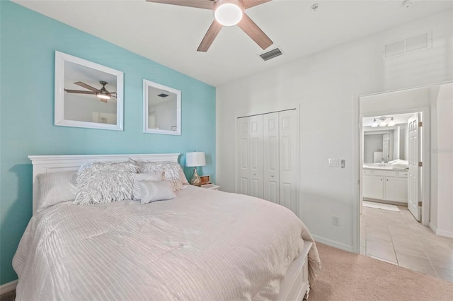 bedroom with ensuite bathroom, ceiling fan, light tile patterned floors, and a closet