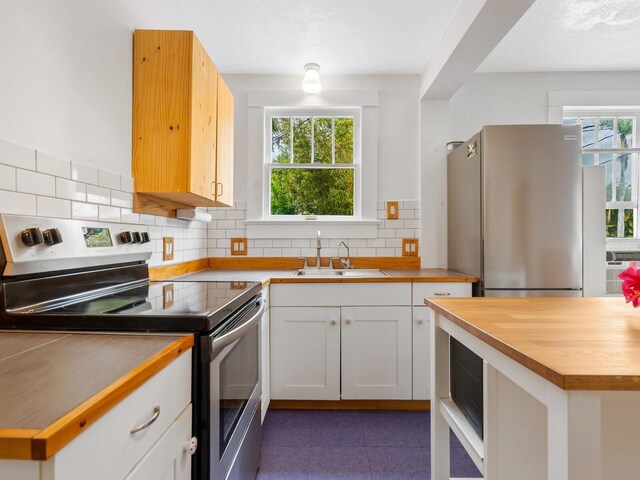 kitchen featuring tasteful backsplash, white cabinetry, sink, and stainless steel appliances