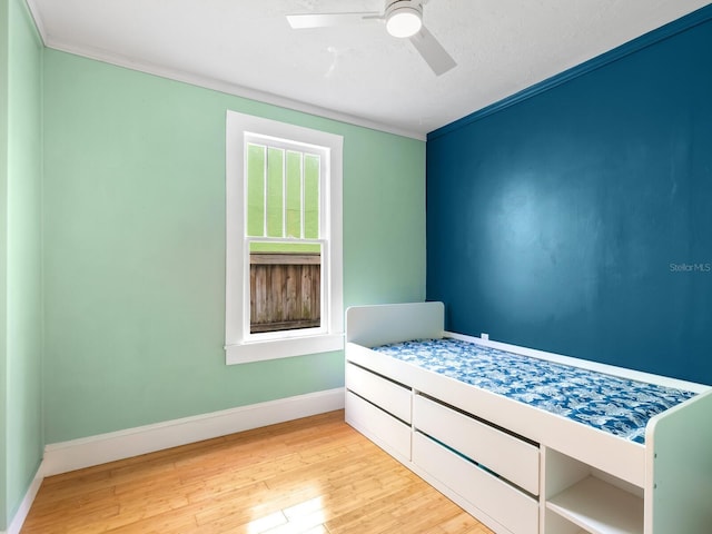 bedroom with ceiling fan, crown molding, and light hardwood / wood-style floors