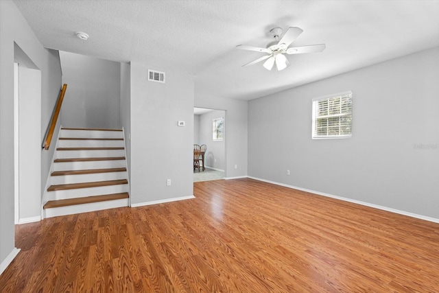 unfurnished living room featuring ceiling fan, hardwood / wood-style floors, and a textured ceiling