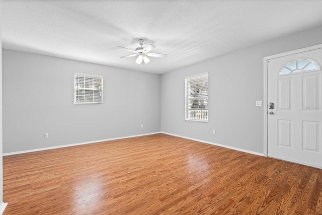 foyer entrance with wood-type flooring, a textured ceiling, and ceiling fan