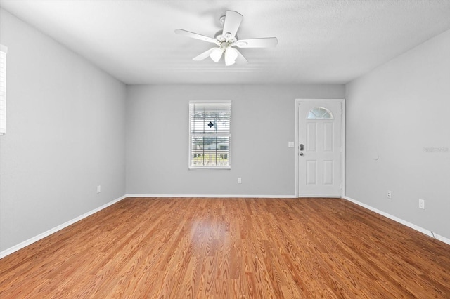 empty room with ceiling fan and light hardwood / wood-style flooring