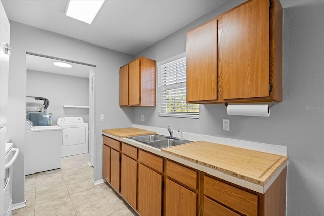 kitchen featuring sink, washing machine and dryer, and light tile patterned flooring