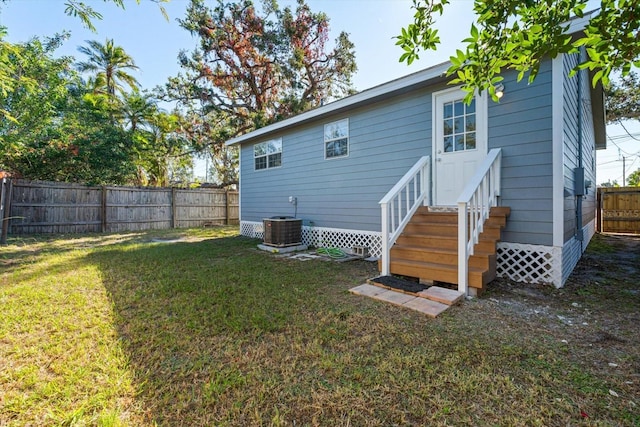 back of property with central AC and a lawn