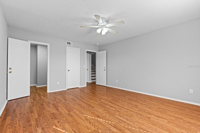 unfurnished bedroom featuring a textured ceiling, ceiling fan, and light hardwood / wood-style flooring