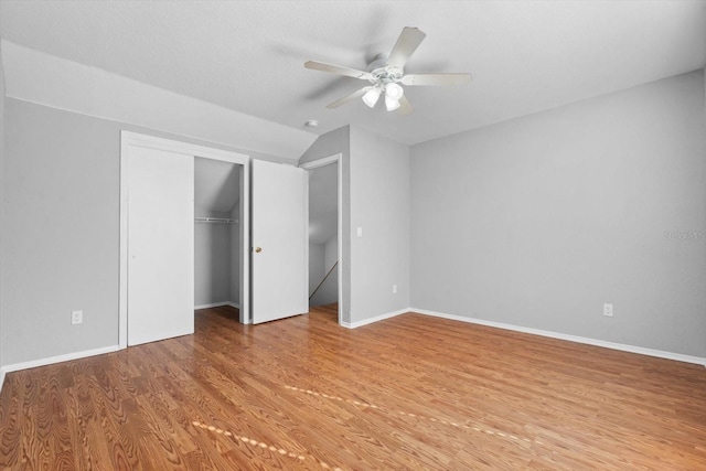 unfurnished bedroom with lofted ceiling, wood-type flooring, a closet, and ceiling fan