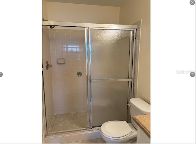 bathroom with tile patterned floors, vanity, toilet, and a shower with door