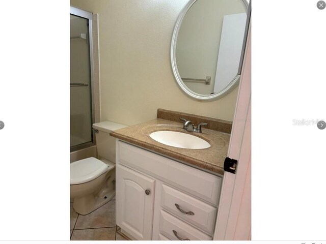 full bathroom featuring tile patterned floors, vanity, bath / shower combo with glass door, and toilet