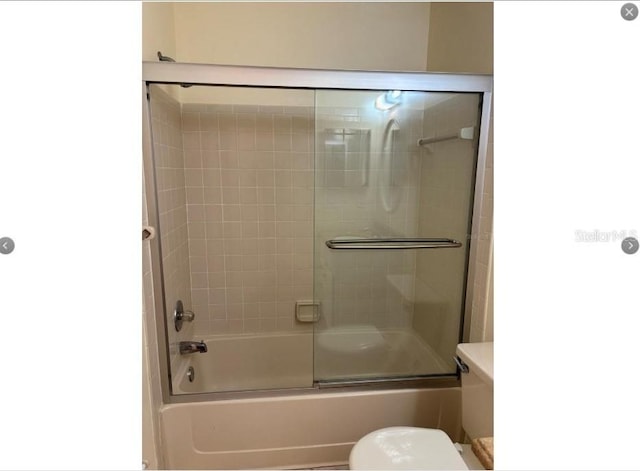 bathroom with enclosed tub / shower combo and toilet