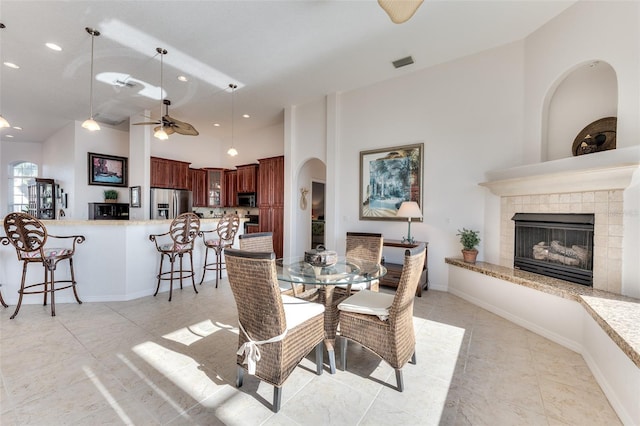 dining area featuring ceiling fan and a tiled fireplace