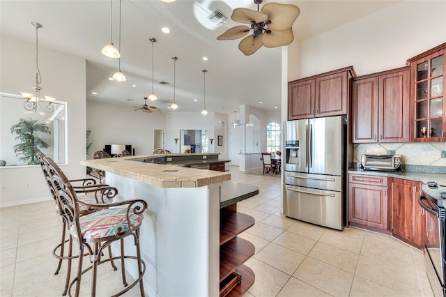 kitchen featuring appliances with stainless steel finishes, ceiling fan with notable chandelier, a breakfast bar area, and pendant lighting