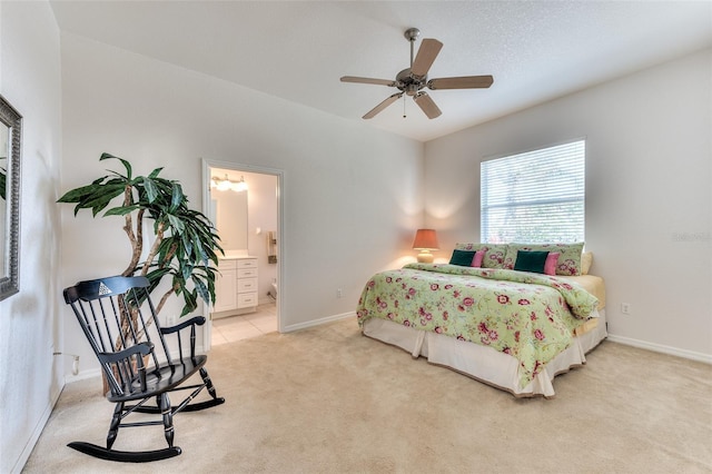 bedroom featuring light carpet, ceiling fan, and ensuite bath