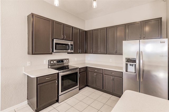 kitchen with dark brown cabinetry, light tile patterned floors, and appliances with stainless steel finishes