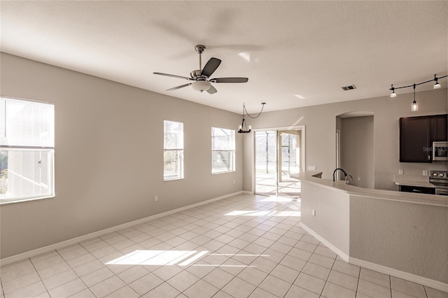 kitchen featuring ceiling fan with notable chandelier, light tile patterned floors, and stainless steel appliances