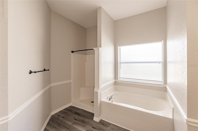 bathroom with wood-type flooring and shower with separate bathtub