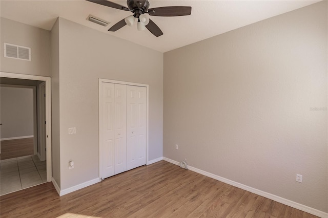 unfurnished bedroom with ceiling fan, a closet, and light wood-type flooring