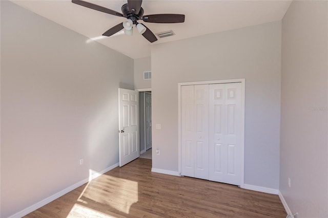 unfurnished bedroom with a closet, ceiling fan, hardwood / wood-style floors, and high vaulted ceiling