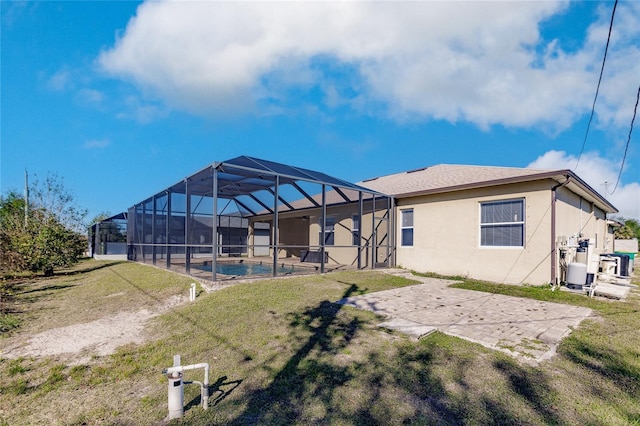 rear view of house featuring glass enclosure, a yard, and a patio