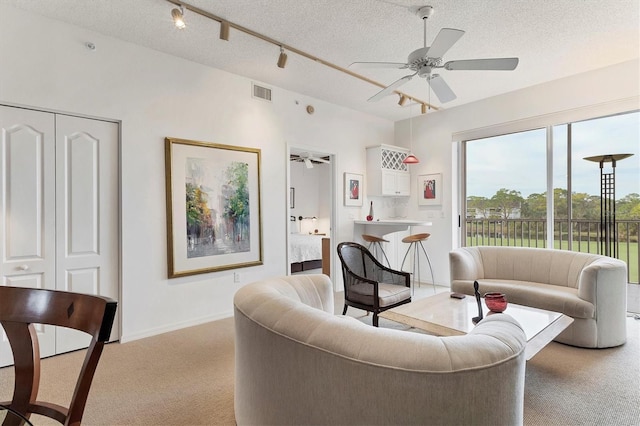 carpeted living room featuring ceiling fan and a textured ceiling