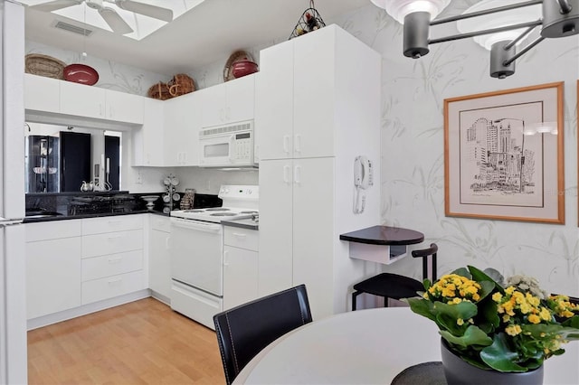 kitchen with white cabinets, light wood-type flooring, and white appliances