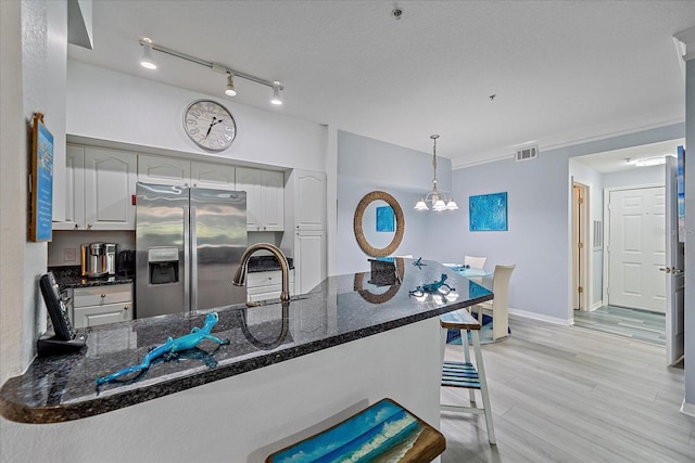 kitchen with white cabinetry, a breakfast bar, stainless steel fridge with ice dispenser, and kitchen peninsula