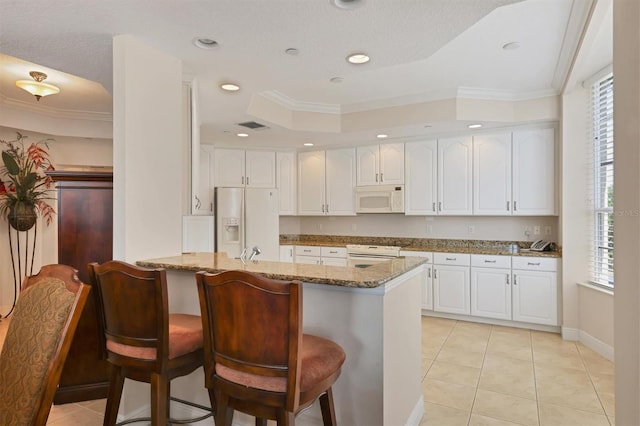 kitchen featuring white appliances, stone counters, kitchen peninsula, light tile patterned floors, and white cabinetry