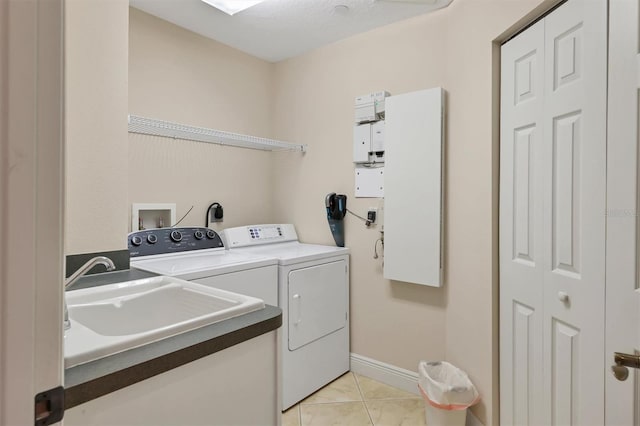 clothes washing area with washing machine and clothes dryer, sink, and light tile patterned floors