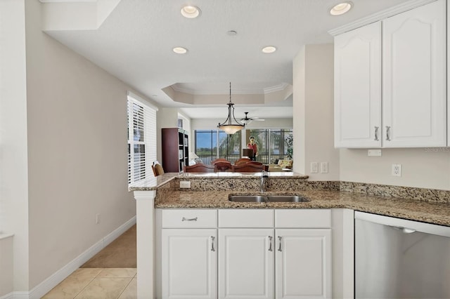 kitchen featuring stainless steel dishwasher, a sink, a peninsula, light stone countertops, and baseboards