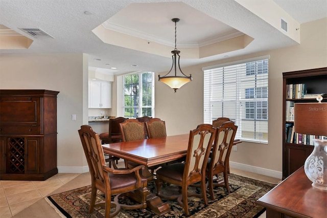 dining room with a tray ceiling, ornamental molding, baseboards, and light tile patterned floors