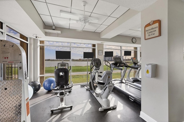 workout area featuring a paneled ceiling, a ceiling fan, and plenty of natural light