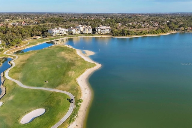 drone / aerial view of a nearby body of water, a local golf course, and a tree filled landscape