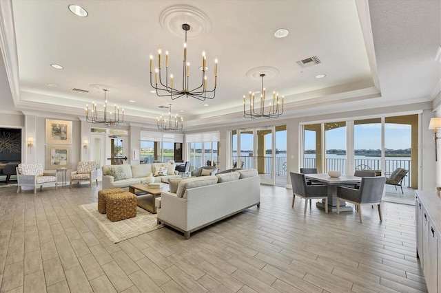 living room featuring a tray ceiling, a chandelier, healthy amount of natural light, and crown molding