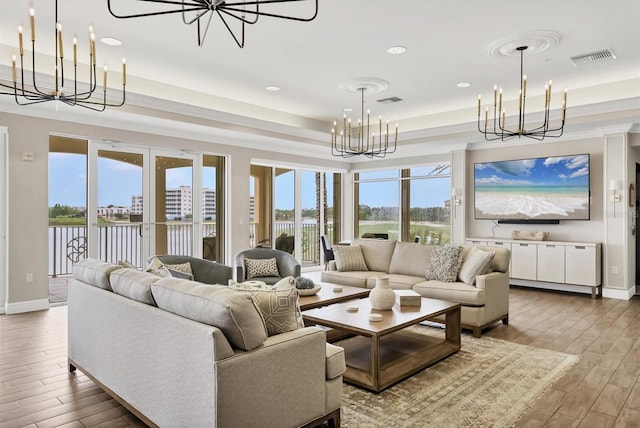 living area featuring a chandelier, wood finished floors, recessed lighting, a raised ceiling, and baseboards