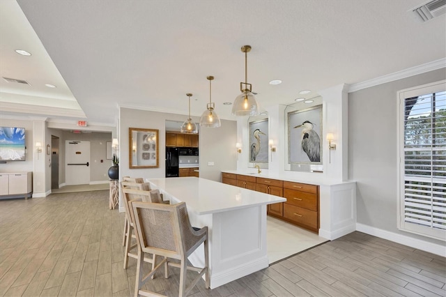 kitchen with freestanding refrigerator, brown cabinets, crown molding, light wood finished floors, and baseboards