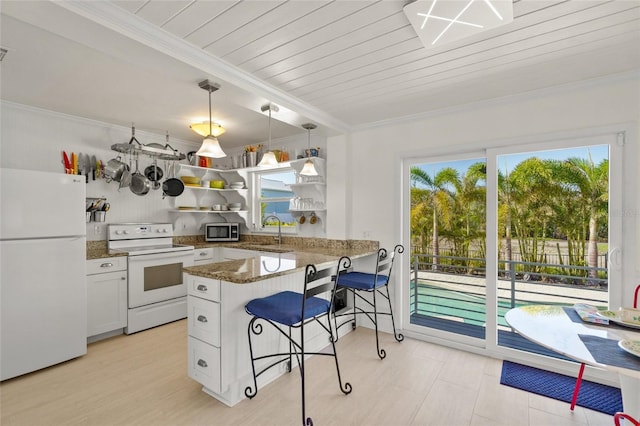 kitchen with kitchen peninsula, pendant lighting, white appliances, a breakfast bar area, and white cabinets