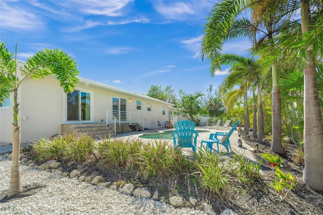 back of property with a fenced in pool and a patio