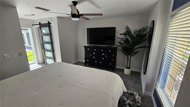 tiled bedroom with a textured ceiling, ceiling fan, and a barn door