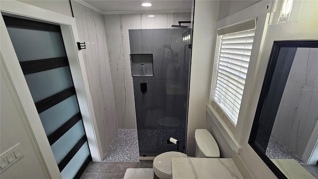 bathroom featuring toilet, a healthy amount of sunlight, tile patterned floors, and a tile shower