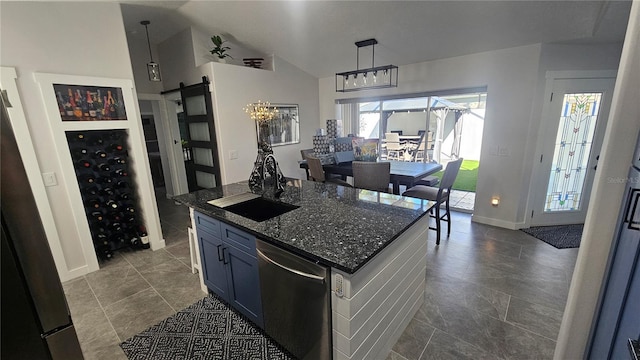 kitchen with appliances with stainless steel finishes, dark stone counters, blue cabinetry, hanging light fixtures, and a barn door