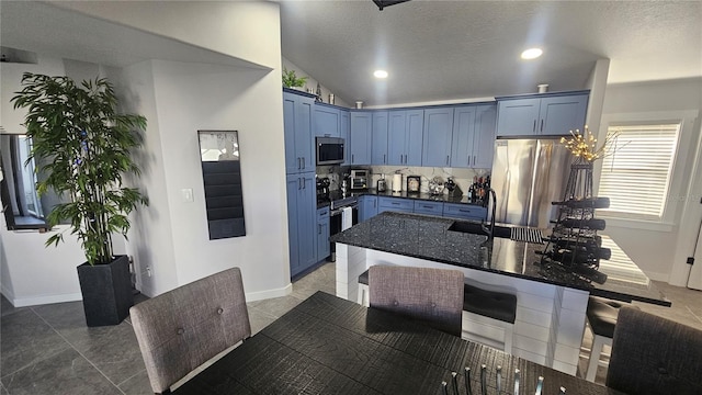 kitchen with lofted ceiling, blue cabinetry, stainless steel appliances, and a sink