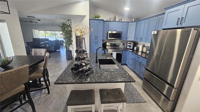 kitchen featuring lofted ceiling, appliances with stainless steel finishes, dark stone countertops, and a kitchen breakfast bar