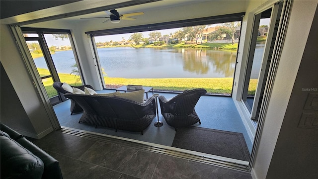 sunroom featuring a ceiling fan and a water view