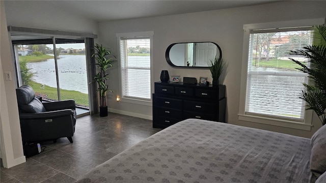 bedroom with access to outside, baseboard heating, a water view, and baseboards