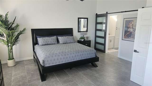 bedroom featuring ensuite bathroom, baseboards, and a barn door