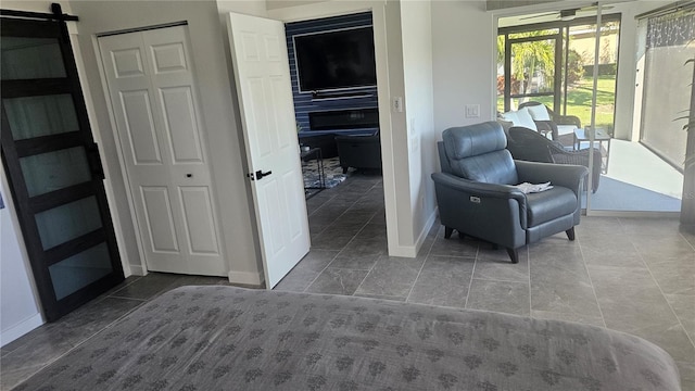 living area featuring a barn door, tile patterned floors, and baseboards