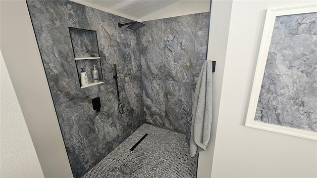 bathroom with a textured ceiling, tiled shower, and vaulted ceiling