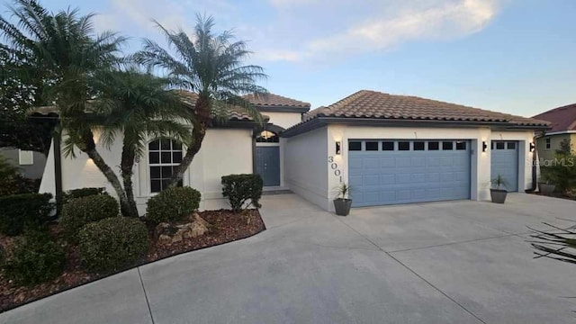 mediterranean / spanish house with a garage, a tile roof, driveway, and stucco siding