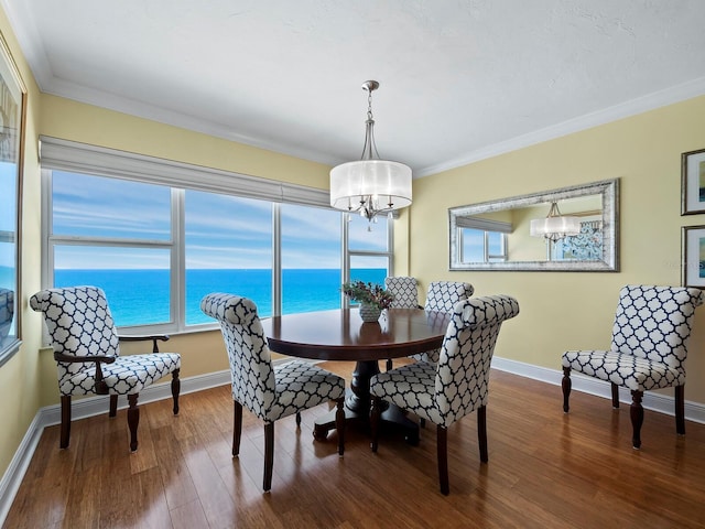 dining room featuring a chandelier, wood-type flooring, a water view, and ornamental molding