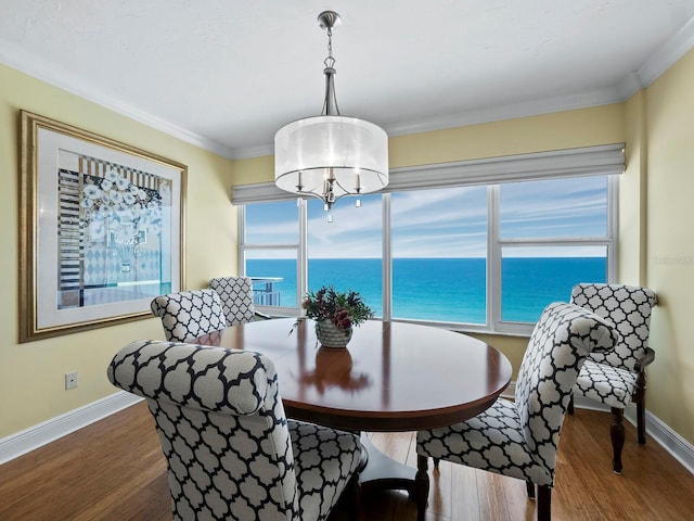 dining room with a water view, wood-type flooring, and crown molding